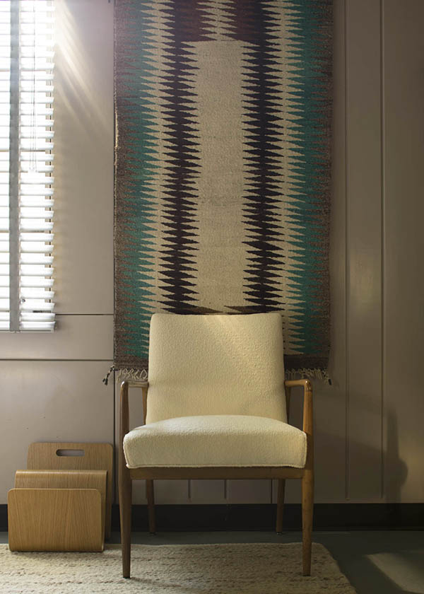 Midcentury white chair with Navajo rug on the wall.