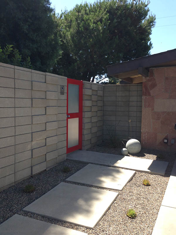 Modern concrete and stone courtyard with red gate